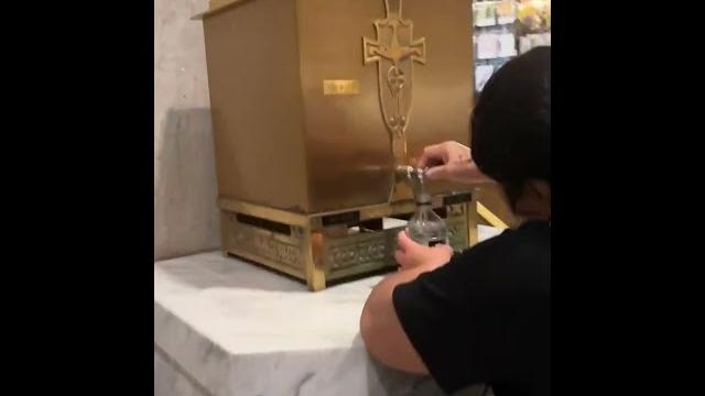 Woman bottles holy water from nyc cathedral Woman bottles holy water from nyc cathedral